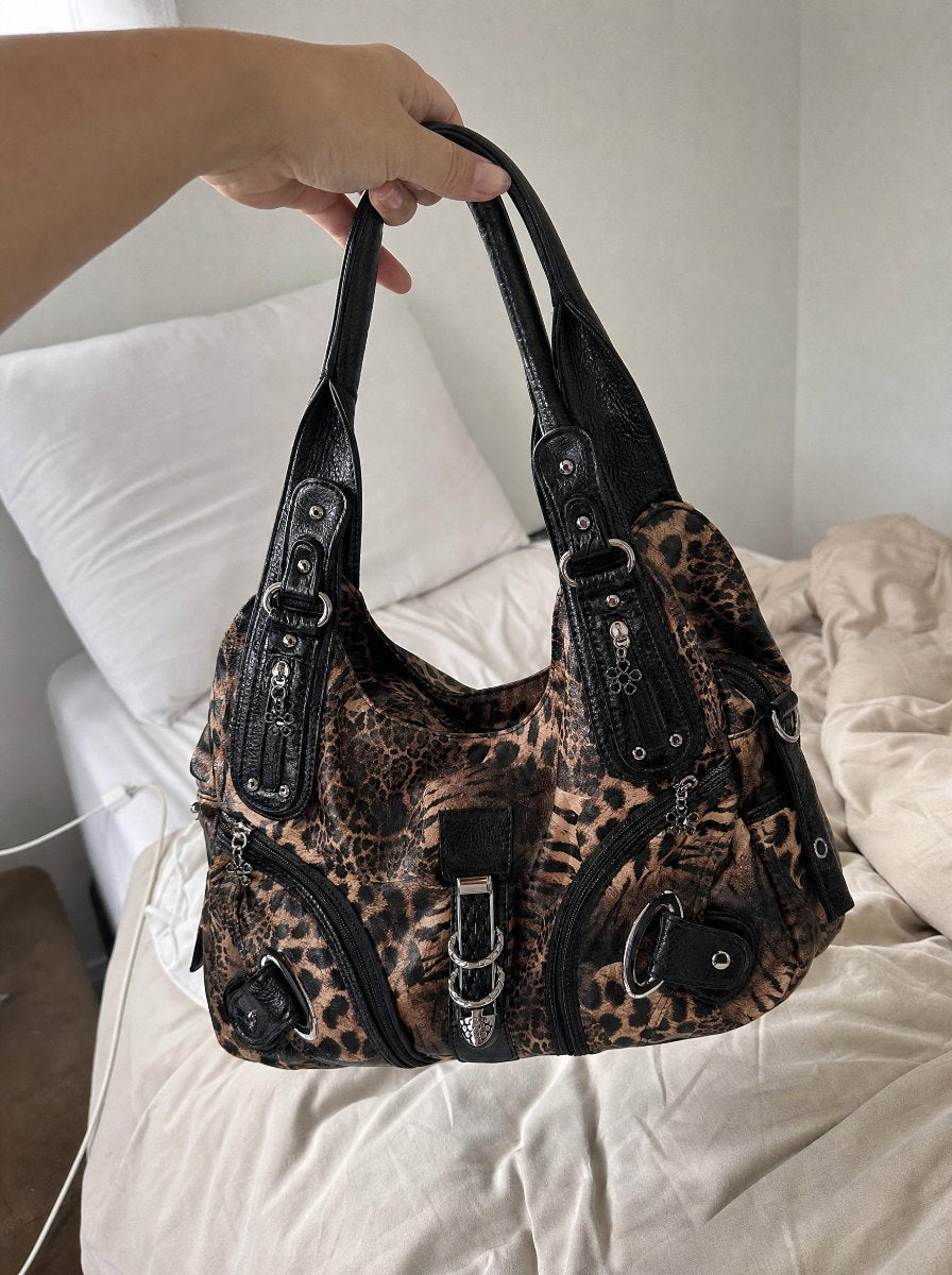 Leopard bag held up by the handles over a bed