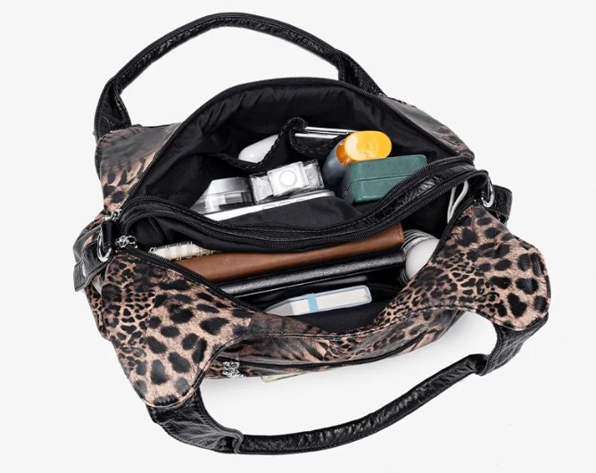 Bag open from above, main compartment packed with a wallet, phone and makeup